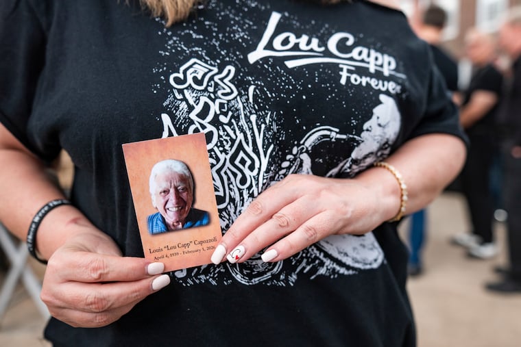 Dyan Capozzoli Wixted stands for a portrait holding a card in memory of her father, Lou Capozzoli, outside Ray’s Happy Birthday Bar in South Philadelphia on Saturday, April 4, 2026. The bar and its patrons celebrate the late owner’s life and birthday with tributes and performances by the Rage Band.