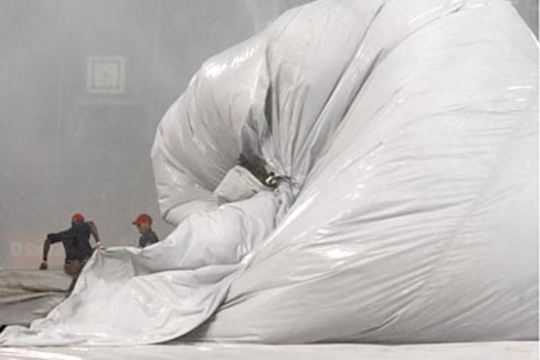 The ground screw had its hands full getting the tarp to stay on the field during the storm. (Clem Murray / Staff Photographer)