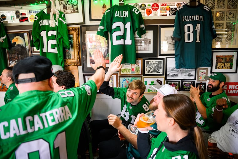 Nick Calcaterra (center) high-fives Andrew Hacker as they watch an Eagles game broadcast at Lombard House in Portland, Ore.