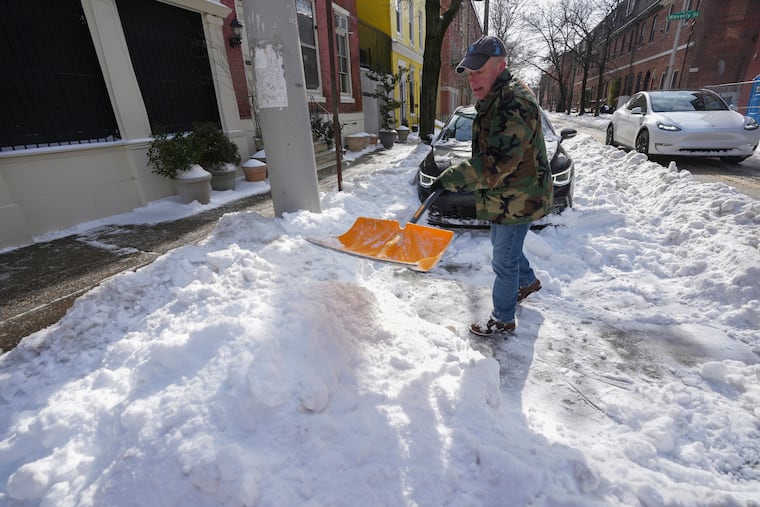 Fred Scheuren shovels snow on 12th Street in Center City in the aftermath of the weekend's significant snow storm.