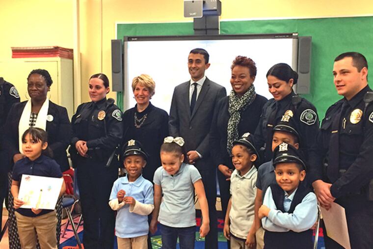 Camden schools Superintendent Paymon Rouhanifard (middle) and Mayor Dana Redd (to the right) pose with Camden County police officers and kindergartners at Bonsall Elementary School after a reading program for the students began Wednesday, Dec. 10, 2014. (Michael Boren/Staff)
