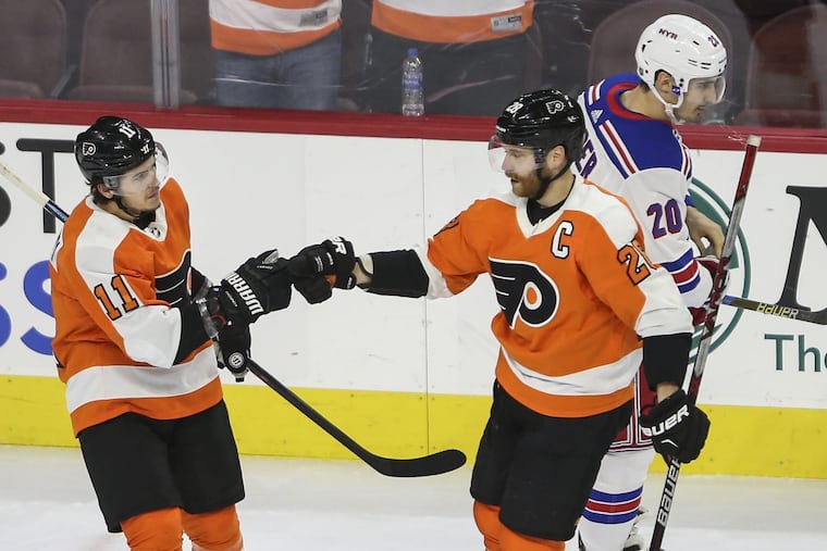 Flyers’ Travis Konecny celebrates his goal with teammate Claude Giroux as Rangers’ Chris Kreider skates by during the first period of the Flyers’ win on Thursday.