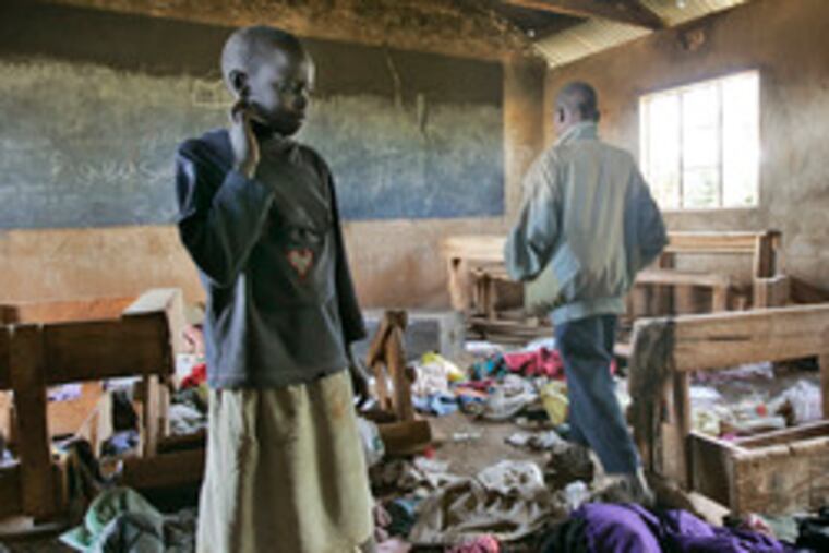 Daisy Chebichi, 10, left, views the destruction in a burned classroomin Ngarua, Kenya. Six people died in the attack on her school. Ngarua is in a part of Kenya dominated by tribes opposed to President Kibaki.