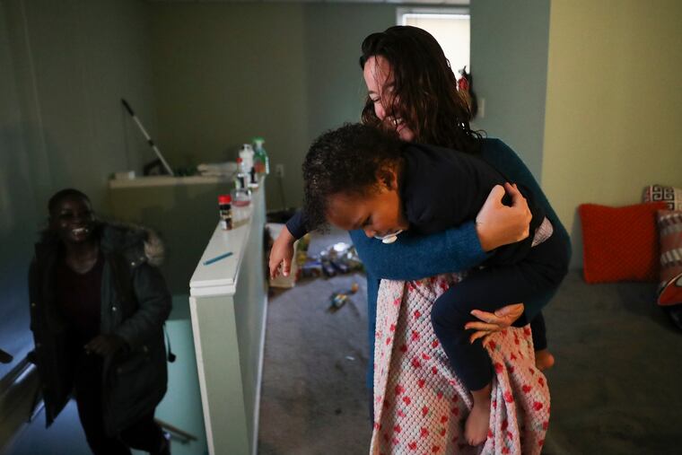 Kori Yancey holds Carter Daily, 2, while his mother, Erica Carter (left), looks on at Carter’s apartment in Lansdale, Pa., on Tuesday, Feb. 1, 2022. Along the Way, a nonprofit based in Montgomery County, provides overnight day care for women who work night shifts.