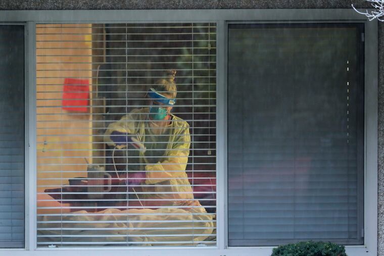 A nurse works in the room of a patient who has tested positive for the COVID-19 coronavirus at the Life Care Center in Kirkland, Wash., near Seattle.