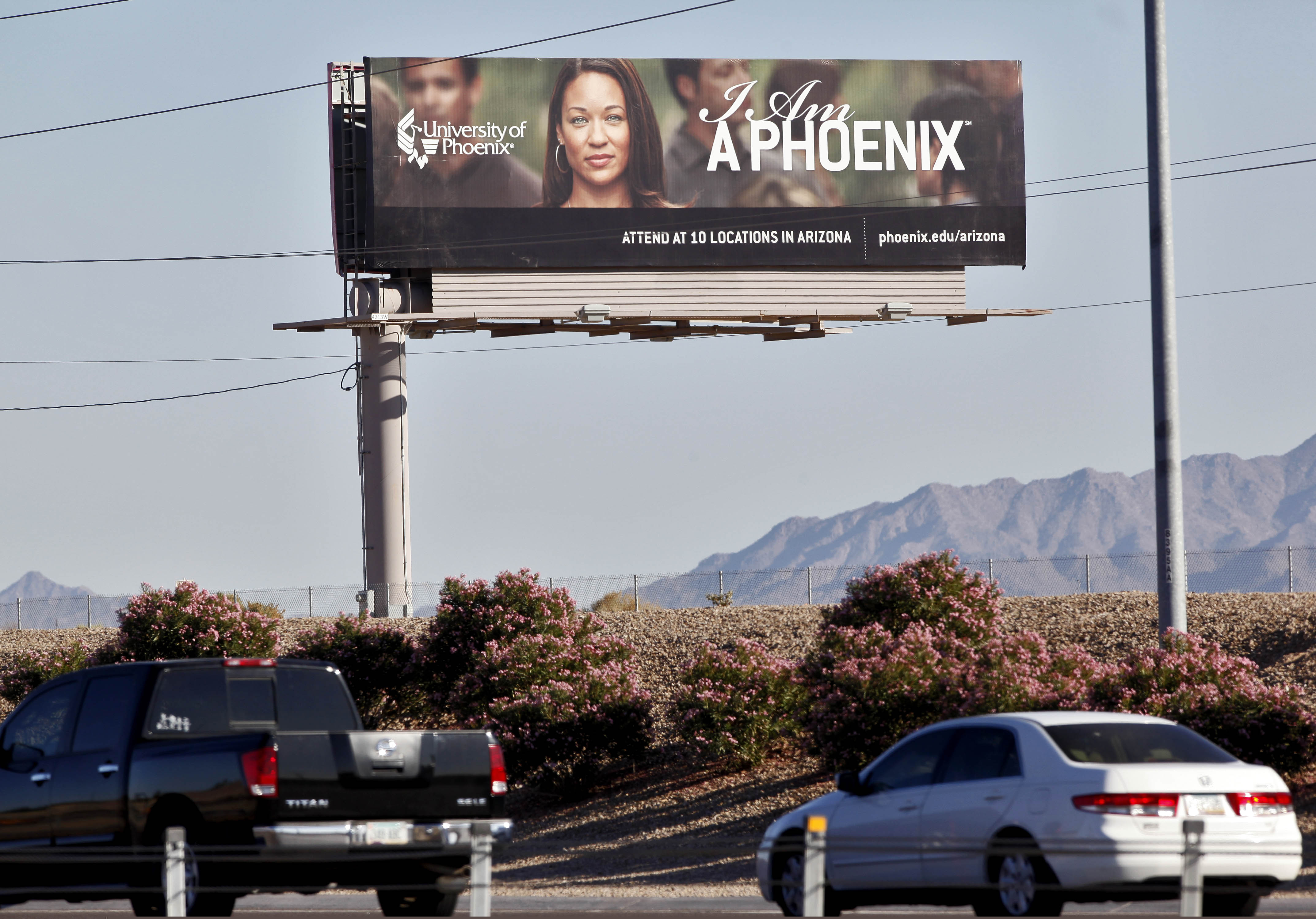 In this Nov 24, 2009, file photo, a University of Phoenix billboard is shown in Chandler, Ariz. The University of Phoenix for-profit college and its parent company will pay $50 million and cancel $141 million in student debt to settle allegations of deceptive advertisement brought by the Federal Trade Commission.