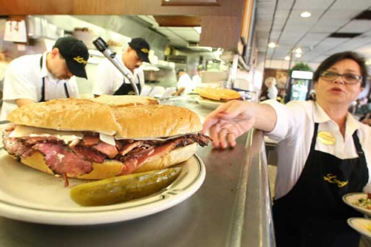 Sheila Abramson, a waitress at Langer's Delicatessen in Los Angeles, California, reaches out for a plate while serving customers on National Pastrami Day on January 14, 2013. Delis are on declining in number, and even landmark locations aren't immune to the industry slide. (Mel Melcon/Los Angeles Times/MCT)