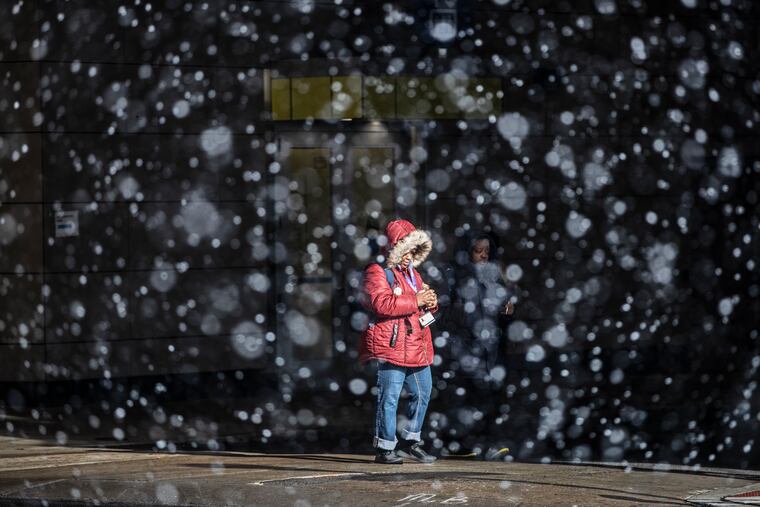 A pedestrian walks south on Eighth Street near Market in January when a squall interrupted a snow-less winter that no one saw coming.