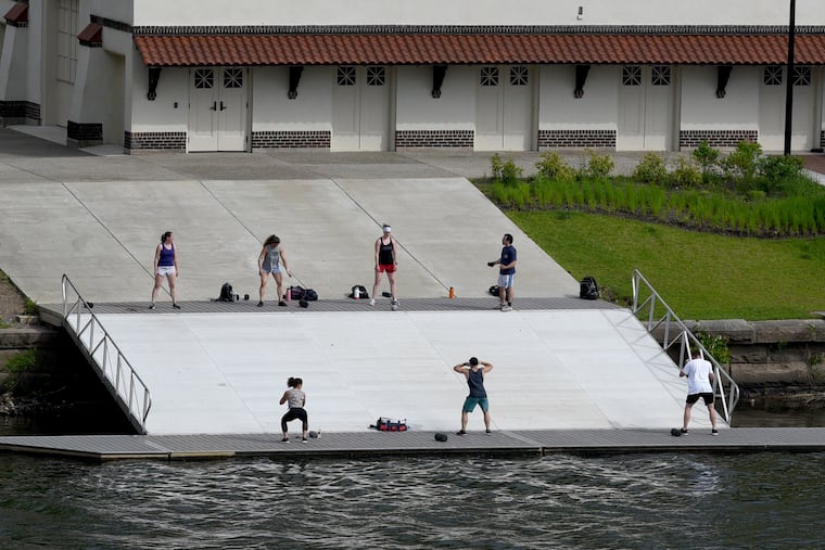 A group practices social distancing while exercising on the dock of the Temple University crew boat house on the Schuylkill River, along Kelly Drive on Friday.