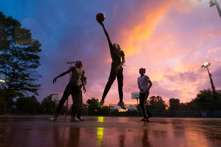 Children play on a rain-slick court after the summer league women's game was called due to the rain last July.