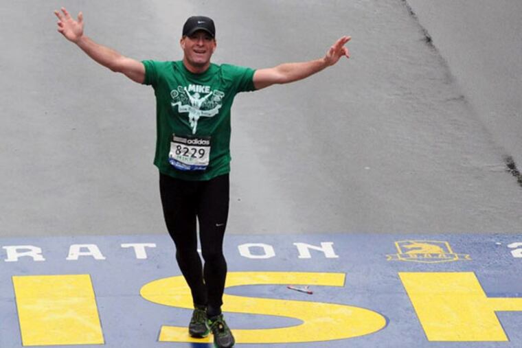 Michael Rossi crosses the finish line of the Boston Marathon. He brought his twin daughters along.