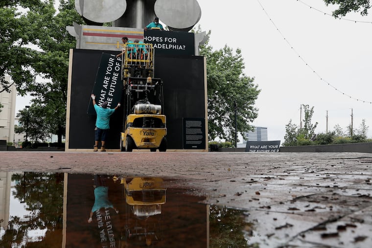 Delaware River Waterfront Corporation workers install signs inviting the public to share ideas at the Christopher Columbus monument at Penn’s Landing in Philadelphia on Thursday, June 18, 2020. The corporation, which maintains the monument, boarded up the bottom of the statue, which is painted so that people can use chalk to write on it while it considers whether to remove it.