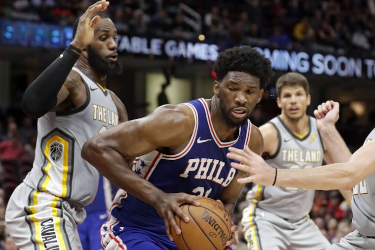 The Sixers' Joel Embiid (center) dribbles against the Cavaliers' LeBron James (left) on Thursday.