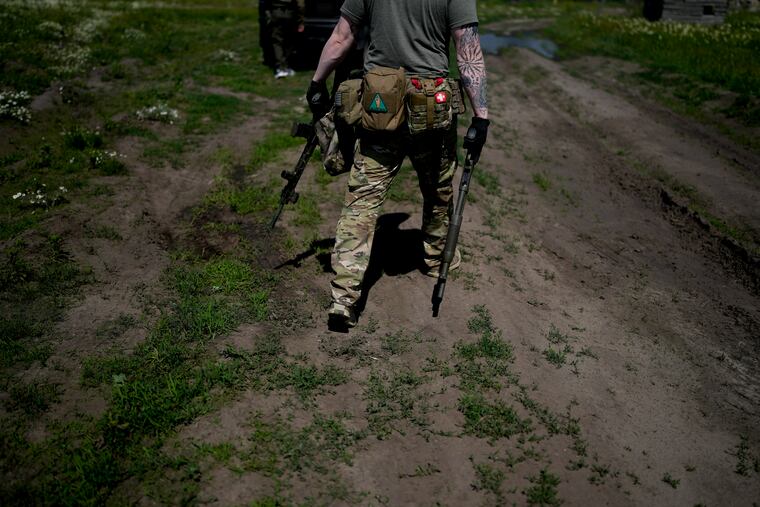 A civilian militia man holds a shotgun and a rifle during training at a shooting range near Kyiv, Ukraine.