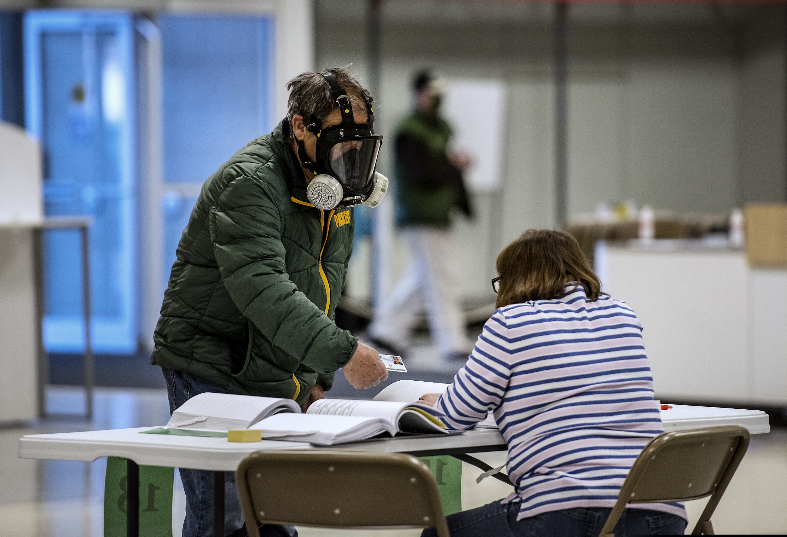 Robert Forrestal, left, wears a full face chemical shield to protect against the spread of coronavirus, as he votes Tuesday, April 7, 2020, at the Janesville Mall in Janesville, Wis. Hundreds of voters in Wisconsin are waiting in line to cast ballots at polling places for the state's presidential primary election, ignoring a stay-at-home order over the coronavirus threat.