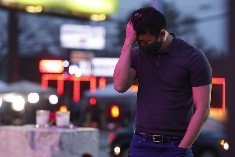 A man pauses Wednesday at a makeshift memorial in front of Gold Spa, one of three Atlanta-area businesses where deadly shootings occurred.