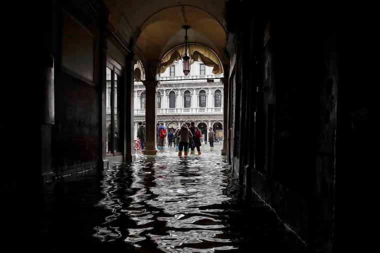 FILE - In this Thursday, Nov. 1, 2018 file photo, tourists walk in the flooded St. Mark's Square in Venice, Italy, as rainstorms and strong winds hit the area. On Thursday, March 28, 2019, the United Nations’ weather agency says extreme weather in 2018 hit 62 million people worldwide last year and created 2 million refugees as man-made climate change worsened. (AP Photo/Luca Bruno)