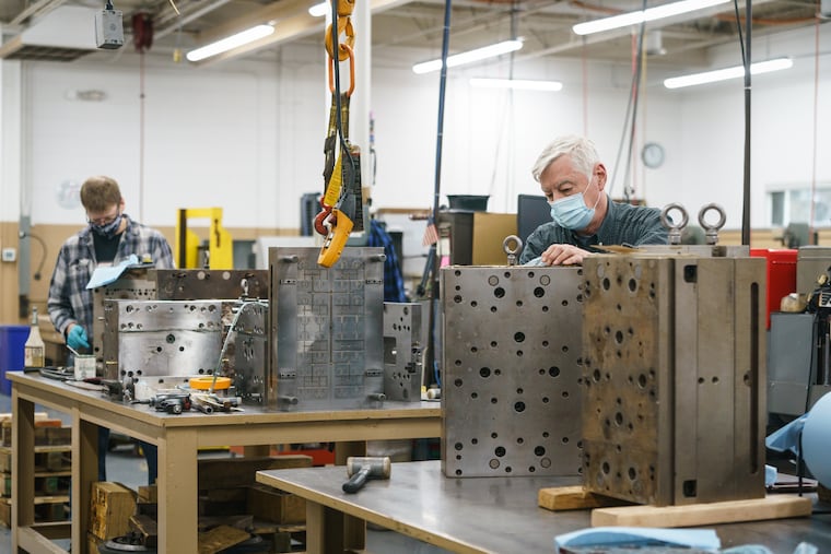 Bob Shafer, front right, a toolmaker who has worked at the Radon Group for 17 years, and Richard Webb, back left, Mold technician,14 years, does maintenance on a mold, at the Rodon Group, a plastic injection molding company in Hatfield, PA, January 18, 2022.