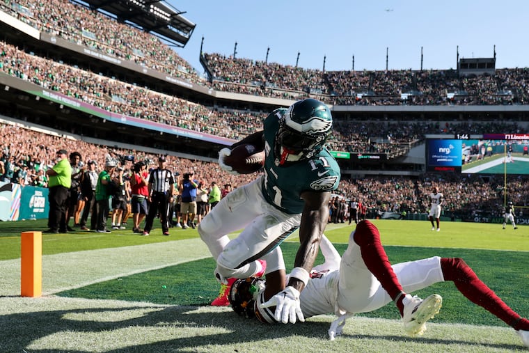 Eagles wide receiver A.J. Brown falls down after catching a late fourth-quarter touchdown past Washington Commanders cornerback Emmanuel Forbes on Sunday, October 1, 2023 in Philadelphia.