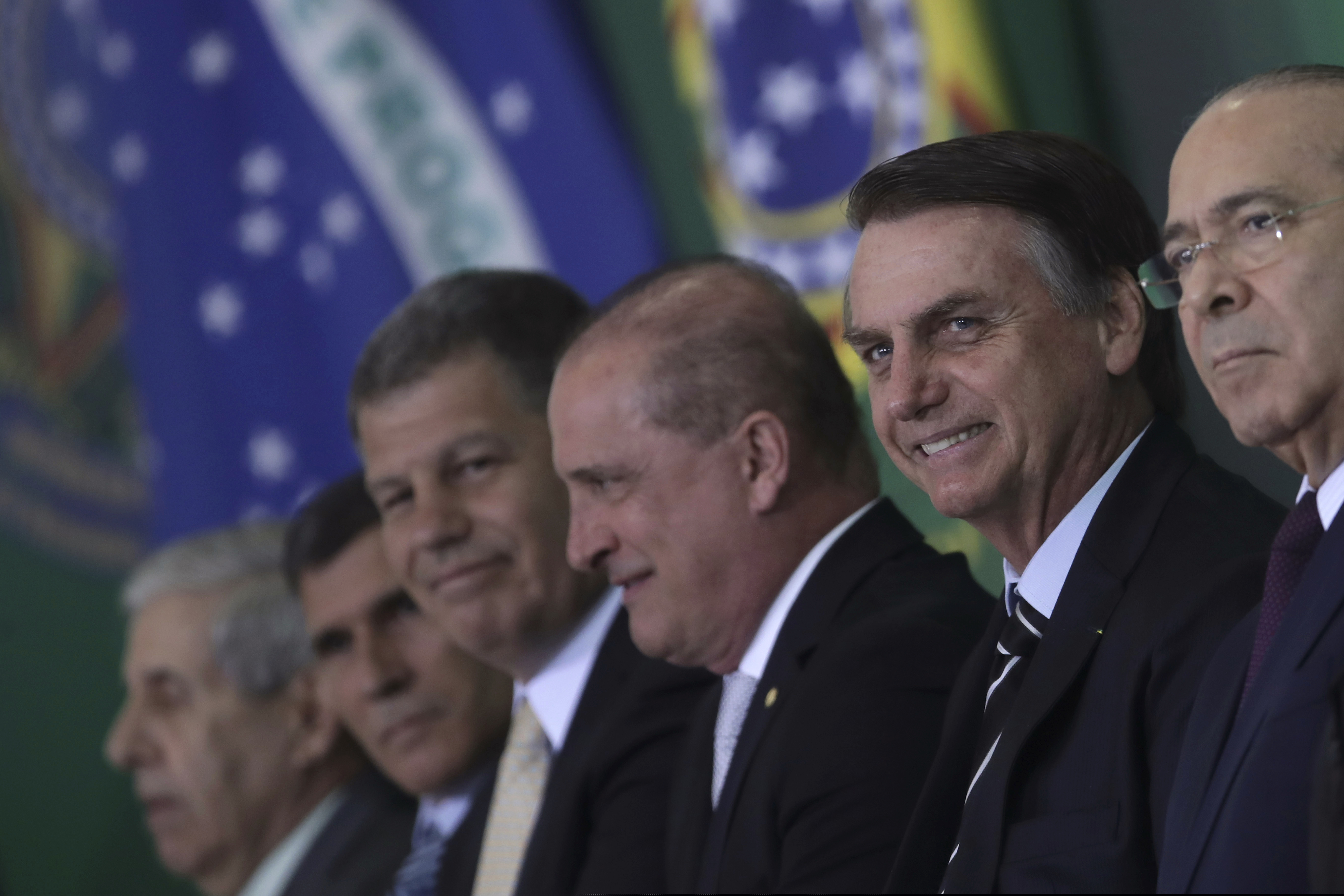 Brazil's President Jair Bolsonaro smiles amid members of his cabinet as he presents them during a ceremony at the presidential palace in Brasilia, Brazil, Wednesday, Jan. 2, 2019. (AP Photo/Eraldo Peres)