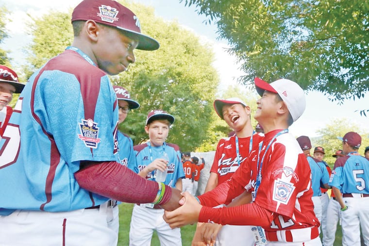 Zion Spearman ( 25 ) of the Taney Dragons meets the Japenese players at the start of the parade in Williamsport, Pa., Wednesday August 13, 2014.