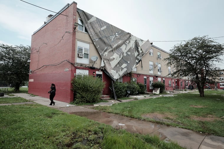 Officials survey the damage to a Philadelphia Housing Authority property at 55th and Vine Streets that had its roof blown off by strong storms that passed thru the area on Saturday.