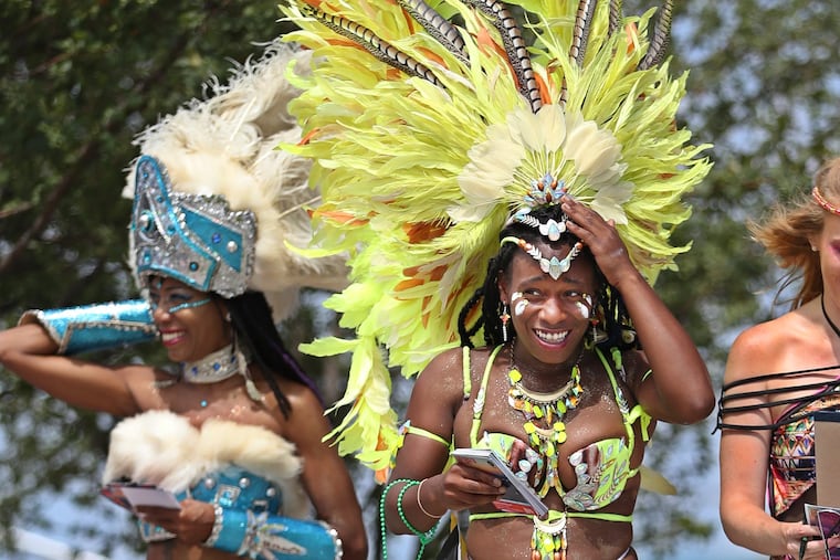 Kristina Hill,right, representing Jamaica, holds onto her headdress as the wind tries to take it off her head as she and Khenti Pratt, left, representing the Bahamas, walk through the 30th Annual Philadelphia Caribbean Festival in 2016.