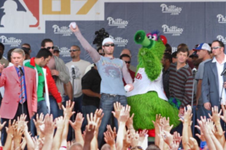 Phillies outfielder Jayson Werth throws out souvenir soft baseballs to the outstretched hands of the fans massing before the stage, which itself was packed with players and other celebrities.
