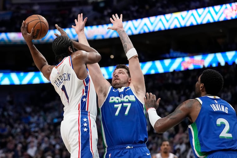 Philadelphia 76ers' James Harden (1) is forced to pass the ball as Dallas Mavericks' Luka Doncic (77) and Kyrie Irving (2) defend.
