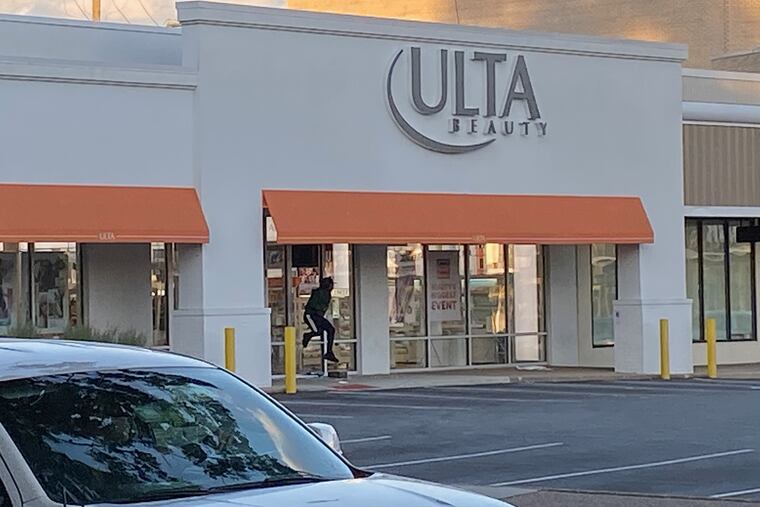 A looter leaps over a barrier while exiting a beauty store on City Avenue at 77th Street in West Philadelphia