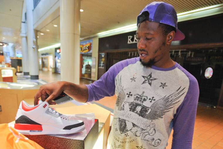 Maurice Holoway, 28 of West Philadelphia inspects the Air Jordans he just bought from the Ubiq shoe store in the Gallery Mall after waiting in line before the store opened. August 4, 2013 (RON TARVER/Staff Photographer)