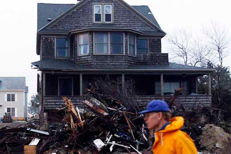 A resident of the Borough of Mantoloking in Ocean County, New Jersey walks past a home with debris from Hurricane Sandy on Sunday, December 17, 2012. ( Yong Kim / Staff Photographer )
NJXMANT18C