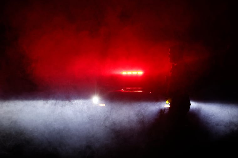 Mantua Township patrolman Alexander Stewart is surrounded by rolling smoke from the flares burning on Mantua Blvd. in Mantua (Gloucester County), N.J. in the early morning hours of Wednesday. Stewart was keeping the road closed so the electric company could make repairs after strong evening storms left a trail of destruction around the area.