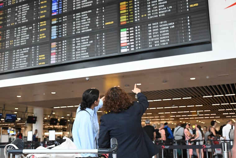 Travelers wait for information in front of a departure board at Brussels International Airport in Brussels on Friday, July 19, 2024.