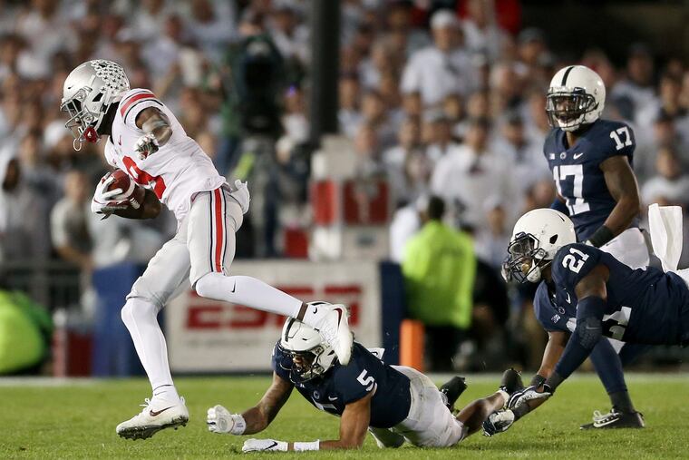 Ohio State receiver Binjimen Victor (left) evades a tackle attempt by Penn State's Tariq Castro-Fields on Victor's fourth-quarter touchdown run on Saturday at Beaver Stadium.