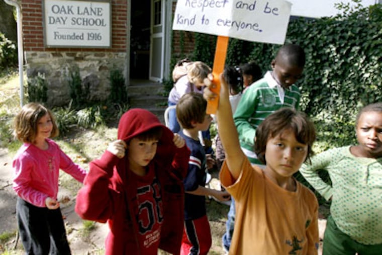 Second and third graders make their way back to the classroom after spending their science class outside on the grounds at the Oak Lane Day School. Julian Whelan, 2nd from right, holds up one of the rules of the day. (Charles Fox / Staff Photographer)