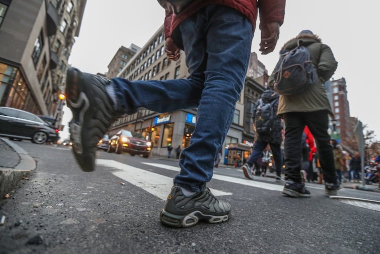 Pedestrians cross the walkway at 16th and Chestnut Street while automobies wait for the light at rush hour.