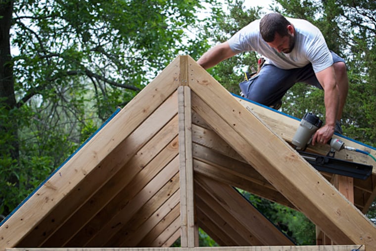Justin Metzler, a contractor by trade, provided his driveway for the construction of the expertly framed tiny house. He is determined to make the house structurally sound and beautiful so there is no protest from towns over its design. LAURENCE KESTERSON / For The Inquirer