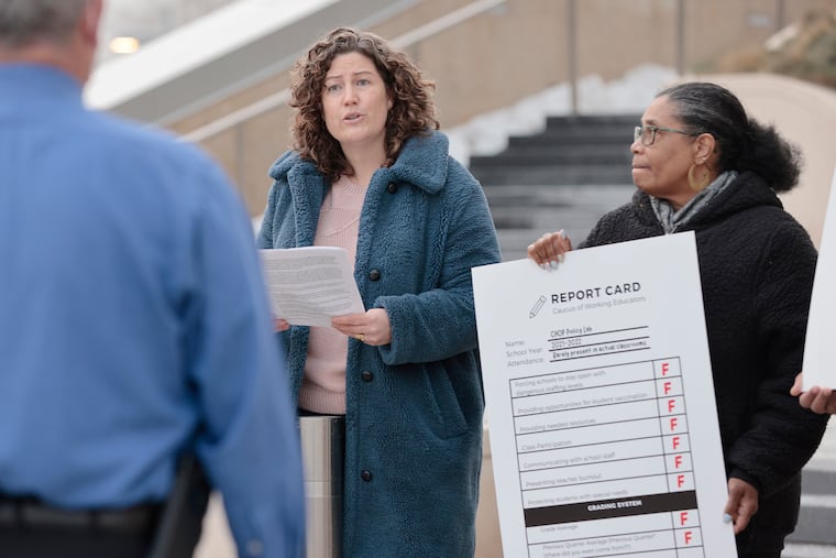 A man representing CHOP (left) listens to Franklin Learning Center teacher Jessica Way (center) read a statement as teacher Kate Sannicks-Lerner (right) looks on. They presented him with their statement and a failing report card for CHOP’s PolicyLab.