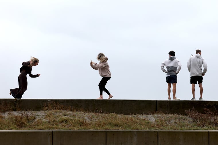 Livvy Stocklin (left) battles the wind as her sister Jacqueline records the scene of last month's beach-eroding No'reaster. This time, the winds will be blowing from the other direction, and may cause "blowout" tides.
