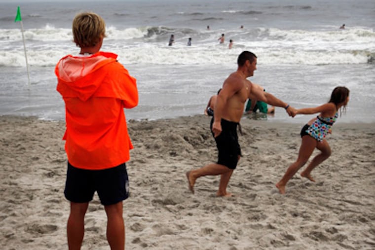 Ocean City Beach Patrol Lifeguard Dan Casey, left, watches wimmers wade in the heavy surf at Ocean City, NJ on Thursday afternoon, August 25, 2011 as Hurricane Irene travels up the coast. (Laurence Kesterson / Staff Photographer)