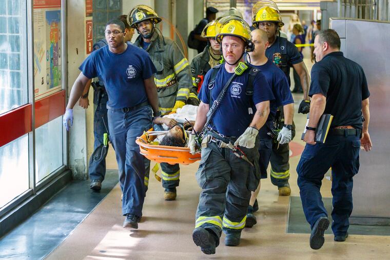 Philadelphia firefighters and emergency responders carry a injured woman out of the PATCO train concourse at Eighth and Market Streets on June 27, 2019.
