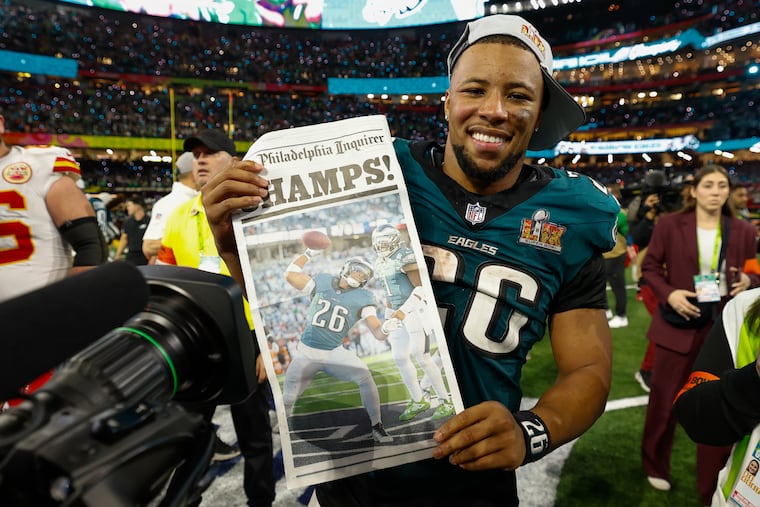 Eagles running back Saquon Barkley holds up an Inquirer newspaper page after the team's Super Bowl LIX win against the Kansa City Chiefs.