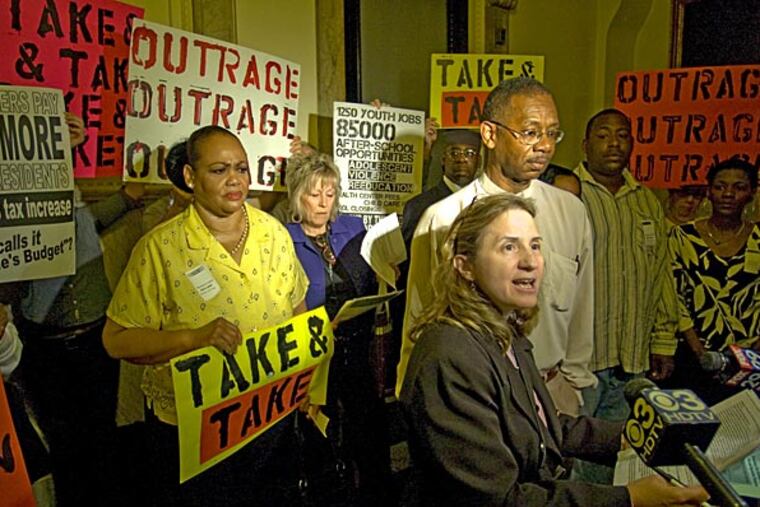 The Coalition for Essential Services, a group comprised of over 30 community-based advocacy organizations and labor unions in Philadelphia, staged a protest outside Council chambers before the start of the weekly council meeting. Sherrie Cohen, with the Rev. Jesse Brown by her side, talks to the media in front of Coalition members holding protest signs.