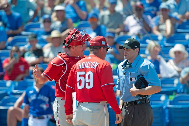 Philadelphia Phillies catcher J.T. Realmuto and manager Rob Thomson argue with umpire Randy Rosenberg after Realmuto was ejected from a spring training baseball game.