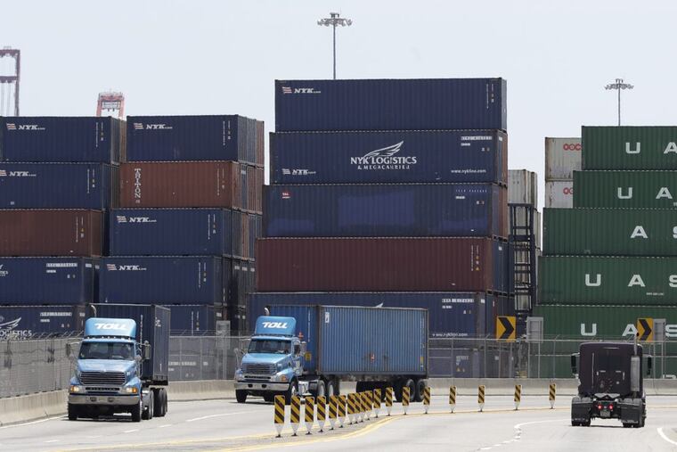 Containers are stacked up as trucks drive by at Port of Elizabeth in N.J., which reports say had trouble with a cyberattack,.