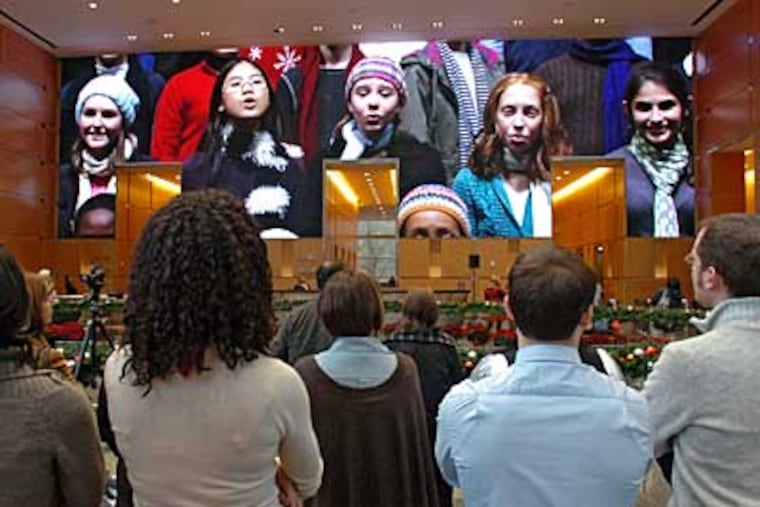 The Commonwealth Youth's Keystone State boys' and girls' choirs sing 'It's The Most Wonderful Time of the Year' as employees watch during Tuesday's preview screening of Comcast's 'Christmas Holiday Spectacular.' ( Clem Murray / Staff Photographer )
