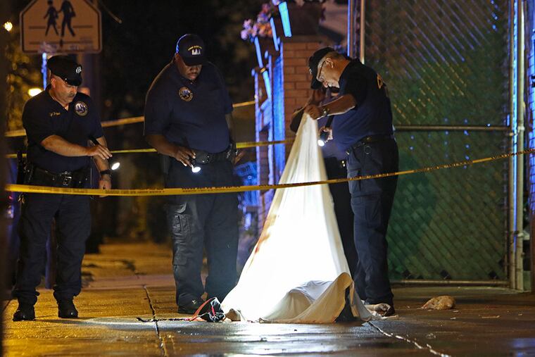 Investigators look under a sheet covering the victim’s body in Olney after the shooting. JOSEPH KACZMAREK / FOR THE DAILY NEWS