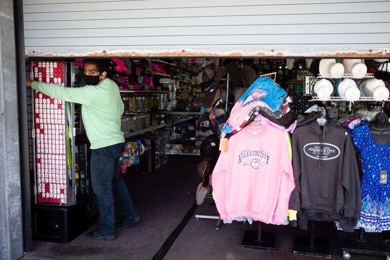 Mohammad Ikram closes a large door to his business Hot Stop, fully stocked but closed during the coronavirus pandemic, on the boardwalk in Atlantic City.