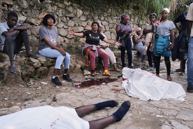 People gather next to the bodies of people they said were their relatives and were killed in a gang attack in the Kenscoff neighborhood of Port-au-Prince, Haiti, Monday, Aug. 24, 2026.